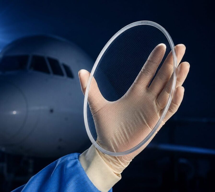 Fenêtre optique en saphir pour applications avioniques, tenue à la main devant le nez d’un avion dans un environnement aéronautique.